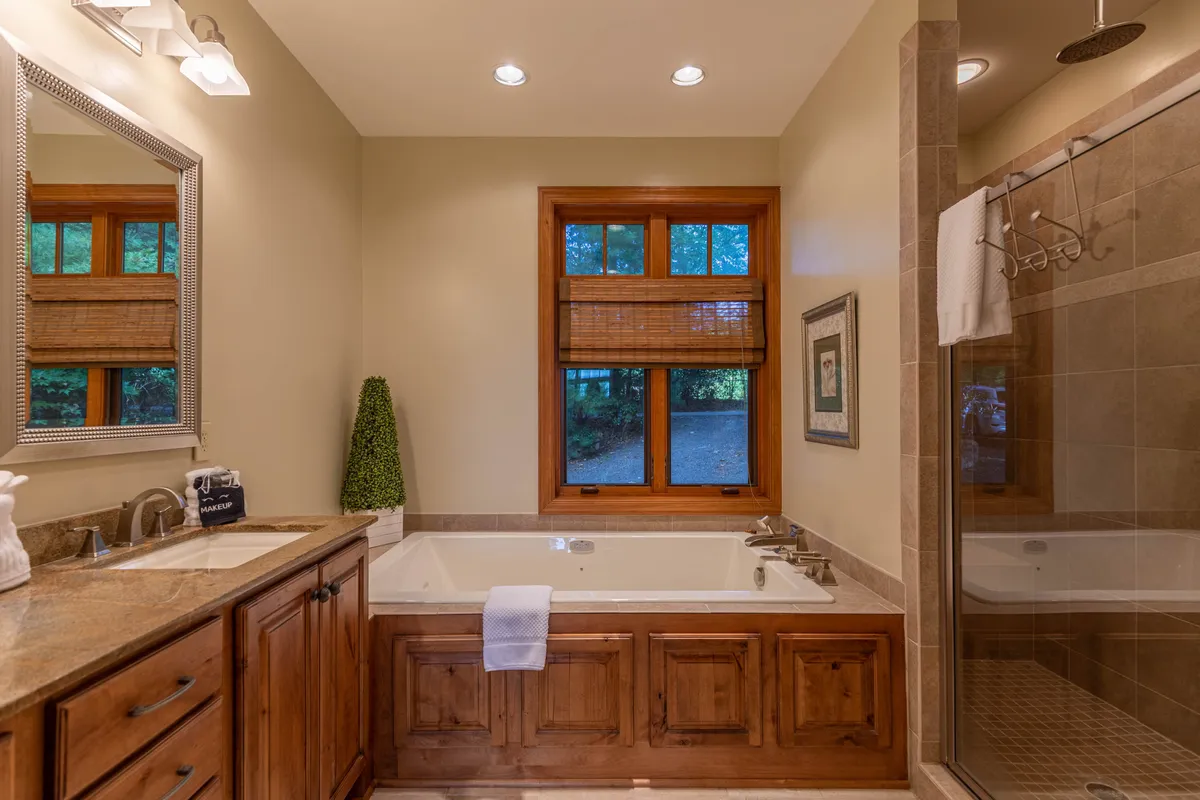 A tranquil bathroom featuring a spacious bathtub, vanity, window bringing in soft natural light, and a modern shower. The space evokes a spa-like atmosphere ideal for relaxation and self-care.