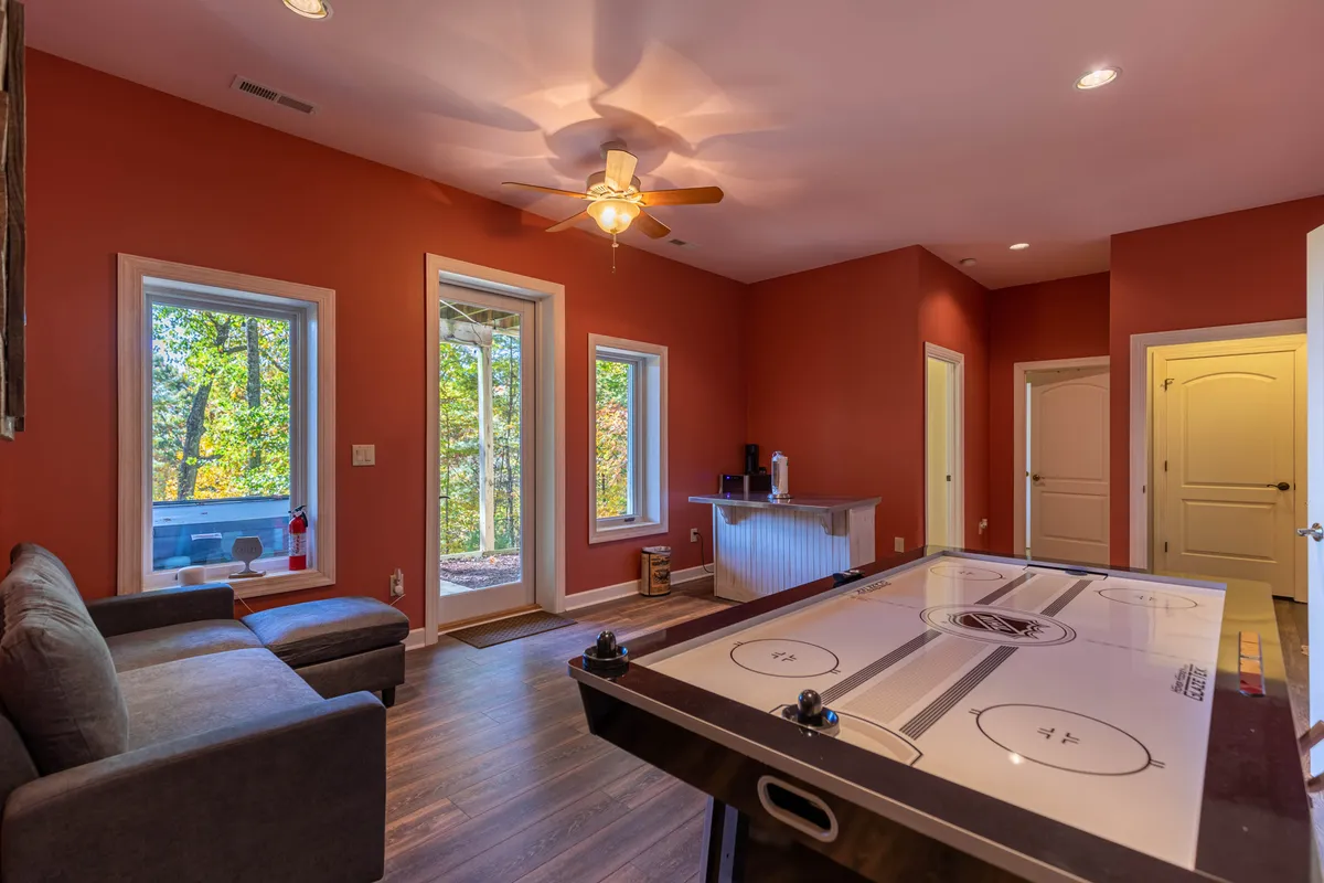 A bright, inviting game area featuring an air hockey table, a plush sofa, and windows that bring in natural light and outdoor views. The space is set up for both games and relaxed conversation.