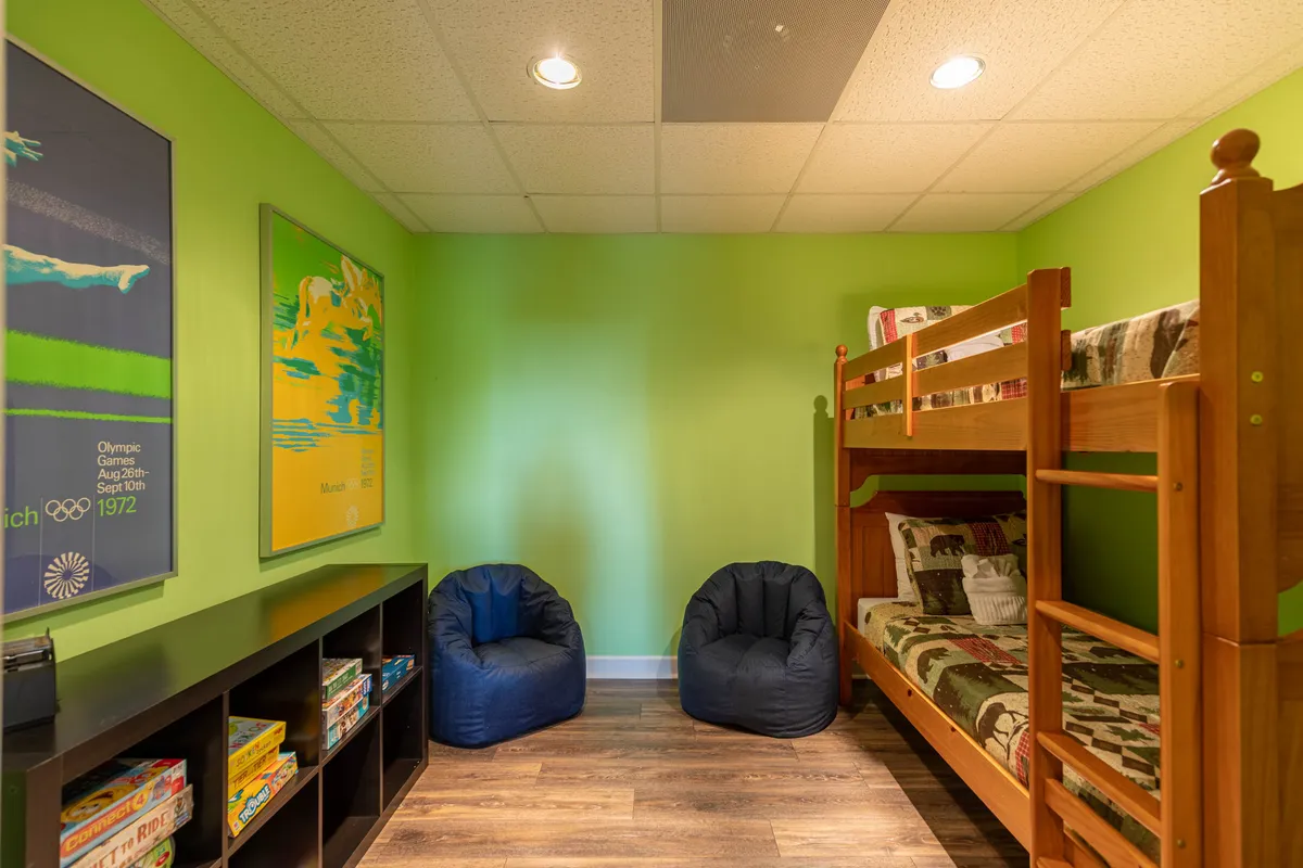 A playful kids’ bunk room with a bunk bed, colorful bean bags, and vibrant wall art. The room feels inviting and fun, with cozy nooks for reading, playing, and winding down after a day of adventure.