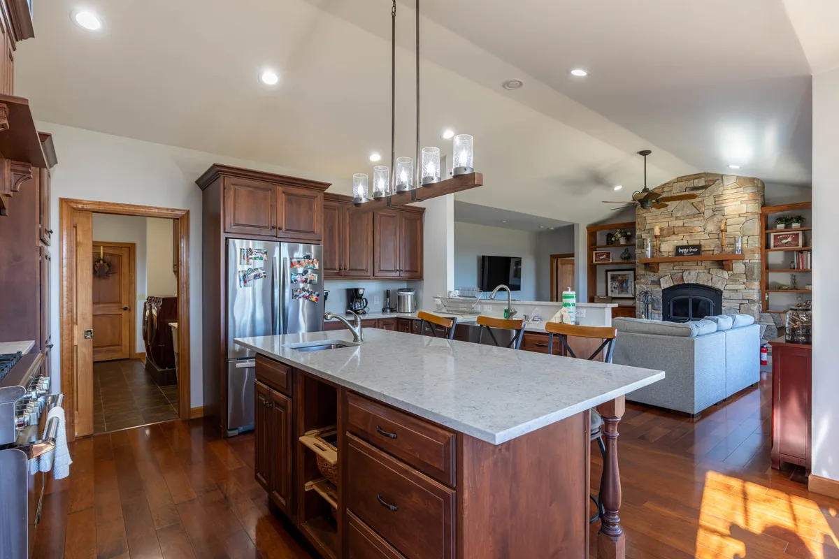 An open-plan space with a welcoming kitchen island, a stone fireplace, and a layout that encourages mingling and entertaining. The ambience is warm and sociable, perfect for group activities and shared experiences.