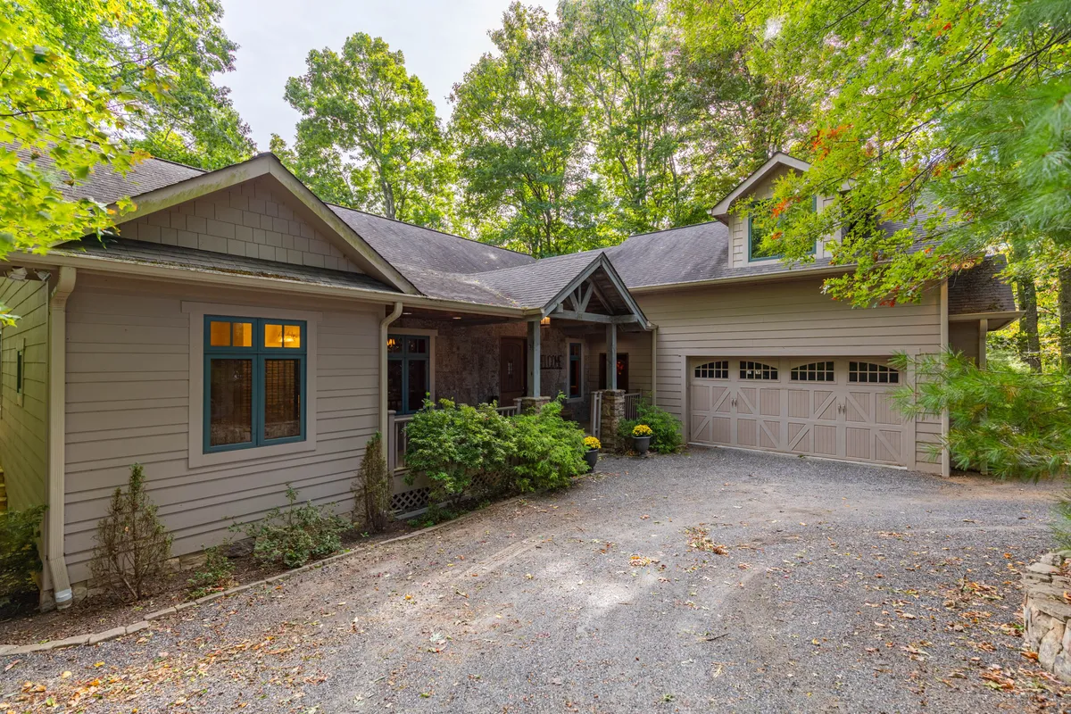 A cozy front porch overlooks a landscaped garden and a tree line, inviting families to gather, relax, and take in the natural surroundings. The scene suggests opportunities for outdoor play, relaxation, or pre- and post-adventure family time.