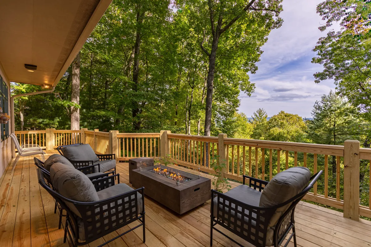 A cozy fire pit area on the wooden deck, surrounded by outdoor seating and embraced by the tranquil setting of mature trees. The deck provides a welcoming space for evening gatherings, relaxation, and enjoying the warmth of the fire.